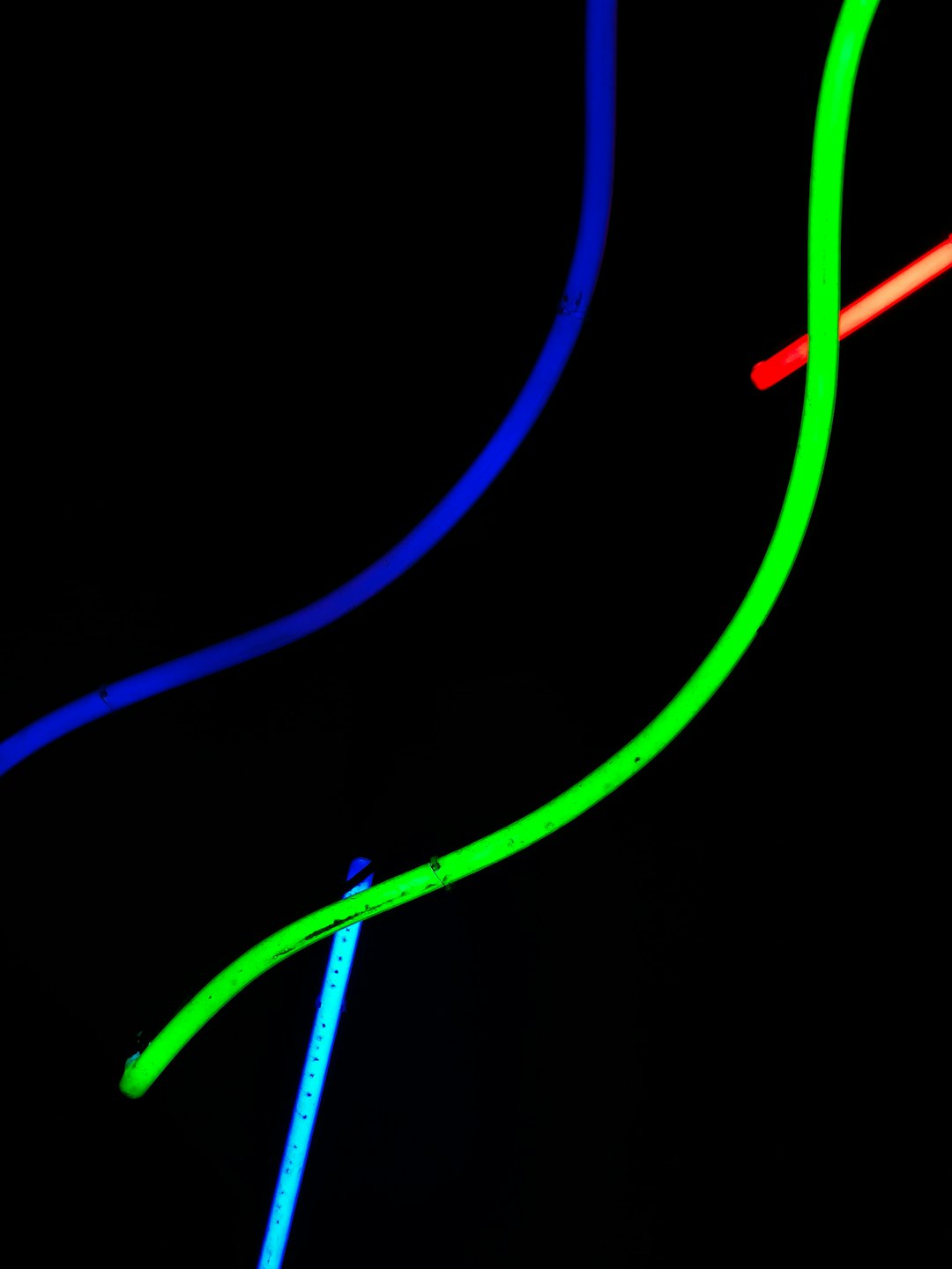 Linee luminose blu, verdi e rosse si intersecano su sfondo nero.